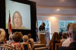 photo - Kibbutz Magen member Shunit Dekel speaks via Skype to those at the Vancouver gathering. Dina Wachtel, executive director, Western Region, Canadian Friends of the Hebrew University, is at the podium