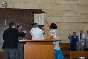 photo - Beth Israel executive director Shannon Etkin lifts the Torah during the dedication of the new building