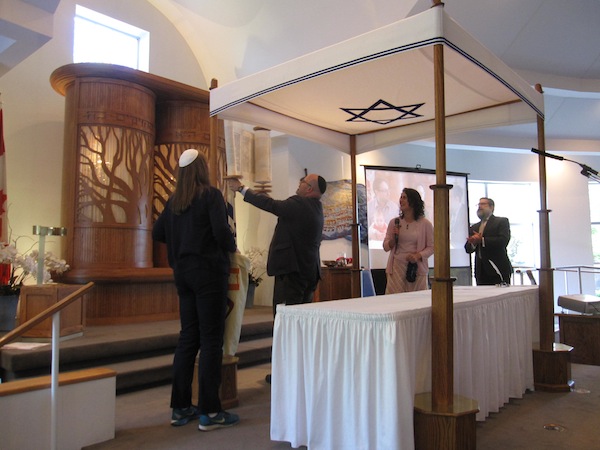 photo - Rabbi Dan Moskovitz raises the newly completed Torah as, left to right, Cantor Naomi Taussig, Rabbi Carey Brown and Rabbi Moshe Druin look on.