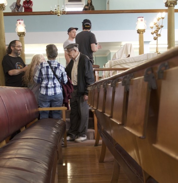 photo - Walk participants explore the Ashkenazi synagogue, the oldest in Winnipeg, on a tour led and organized by Zach Fleisher, seen below in front of what used to be the building housing the city’s Hebrew Sick Benefit Association. (photo from Zach Fleisher)