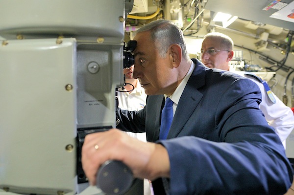 photo - Prime Minister Binyamin Netanyahu looks through the periscope of the latest submarine to be delivered to the Israeli navy by the German government