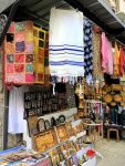 photo - Knowing that, in any one day, hundreds of visitors will pass their shops, usually on the way to the Kotel (Western Wall), shopkeepers in Jerusalem’s Old City stock as many items as possible to appeal to all religions. Prayer shawls, rugs, crosses and ritual items of every size and description are available, as are religious paintings and carvings, key holders and the like)