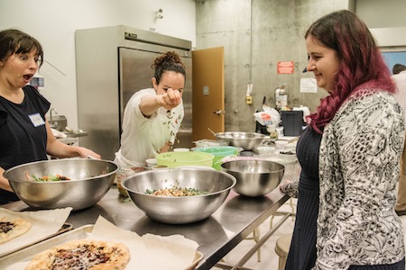 photo - Chef Lior Ben-Yehuda puts the finishing touches on a salad as Erika Balcombe, left, and JMABC archivist Alysa Routtenberg look on