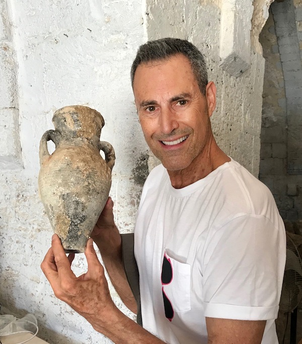 photo - Uri Geller holds a water or oil jug that was found during the construction of a new museum dedicated to his activities