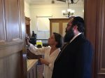 photo - Selina Robinson, B.C. minister of municipal affairs and housing, admires the new mezuzah on her office door, while Rabbi Yechiel Baitelman looks on