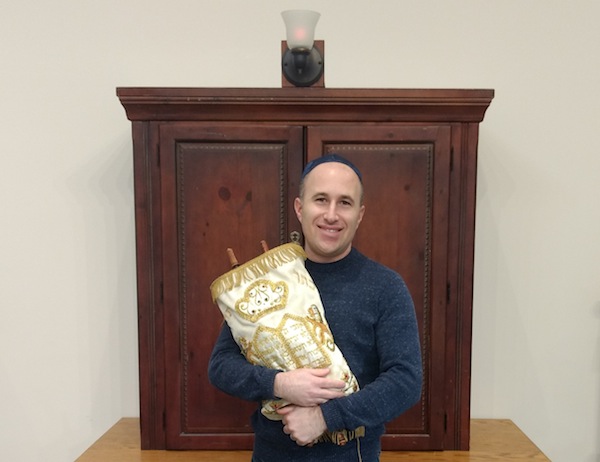 photo - Rabbi Joshua Samuels holds the congregation’s Torah from Lithuania