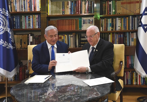 photo - Prime Minister Binyamin Netanyahu, left, and President Reuven Rivlin hold the agreement that allows Netanyhau another two weeks to try and form a coalition government