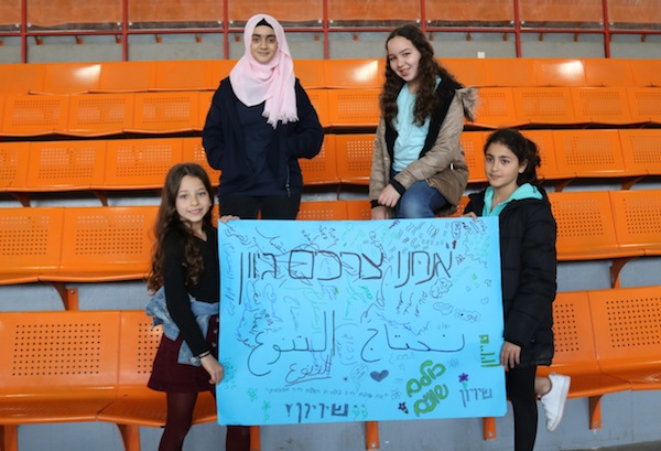 photo - Children in the Arab village of Kalansua with a poster stating, “We need diversity” and “We are all equal” in Hebrew and Arabic
