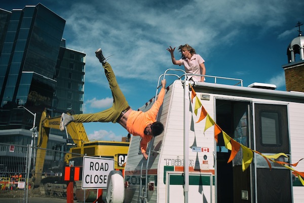 photo - Ben Gorodetsky hangs on to an RV’s ladder in There Yet by Edmonton’s Mile Zero Dance
