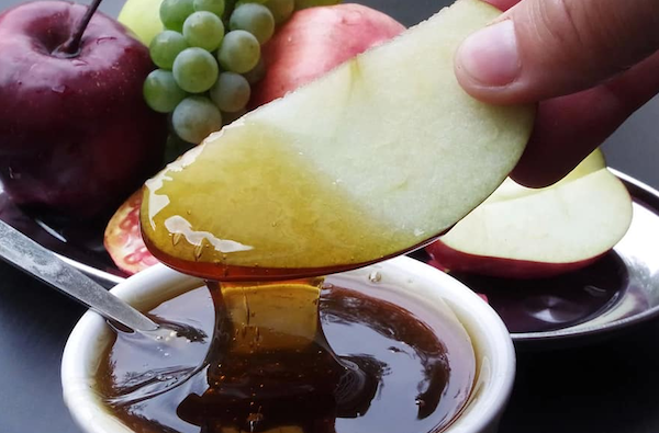 photo - an apple being dipped in honey