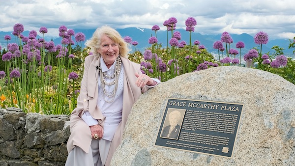 photo - Mary McCarthy Parsons sits in Grace McCarthy Plaza, beside the plaque that briefly describes her mother’s contributions to the city and the province