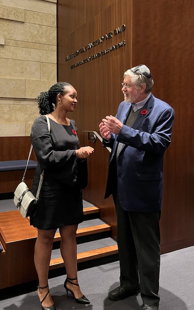 photo - Liliane Pari Umuhoza speaks with Prof. Chris Friedrichs at the Kristallnacht commemoration, which took place at Beth Israel