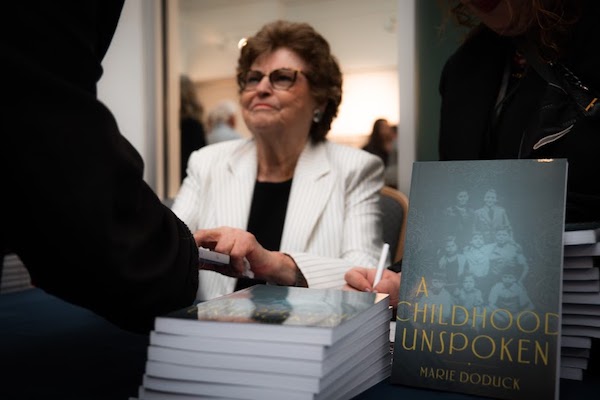 photo - Marie Doduck speaks with a guest at the launch of her book A Childhood Unspoken on Jan. 22