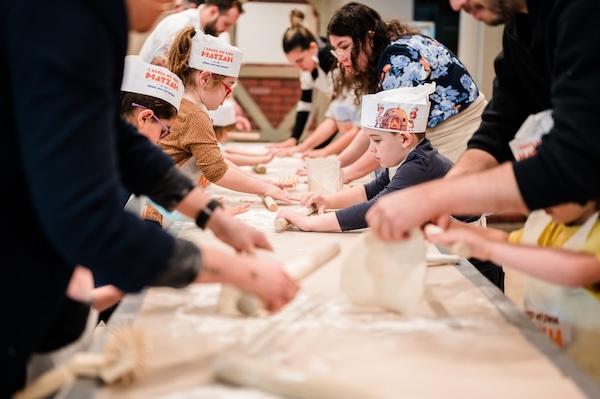 photo - participants making matzah at the Lubavitch BC Model Matzah Bakery in 2024