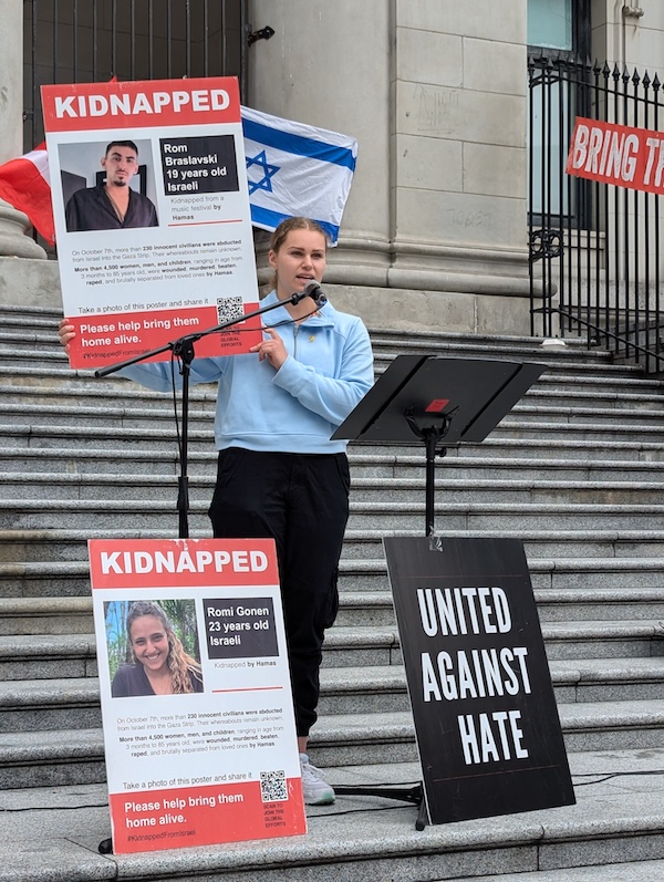 photo - UBC student Zara Nybo, a non-Jewish ally, holds a poster of Rom Braslavski, as she speaks of his heroism before he was taken hostage to Gaza on Oct. 7