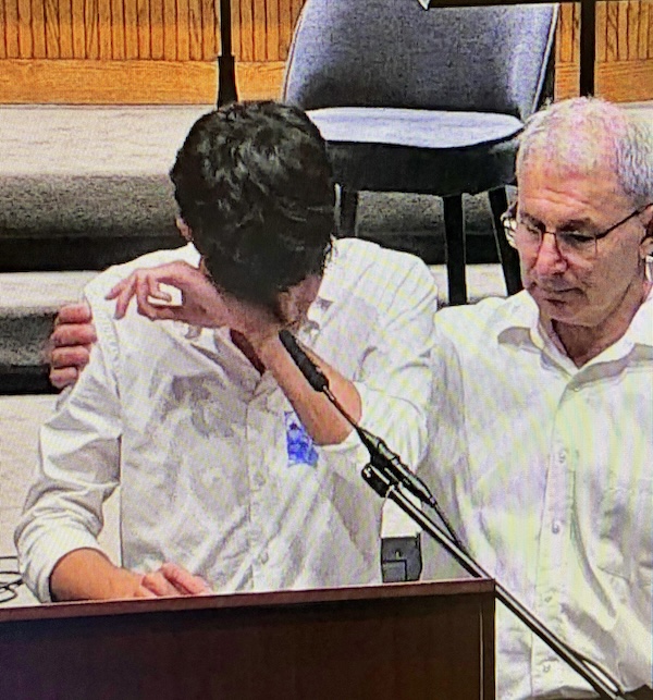 photo - Geoffrey Druker, who leads the community’s annual memorial ceremony, consoles a young speaker on Yom Hazikaron