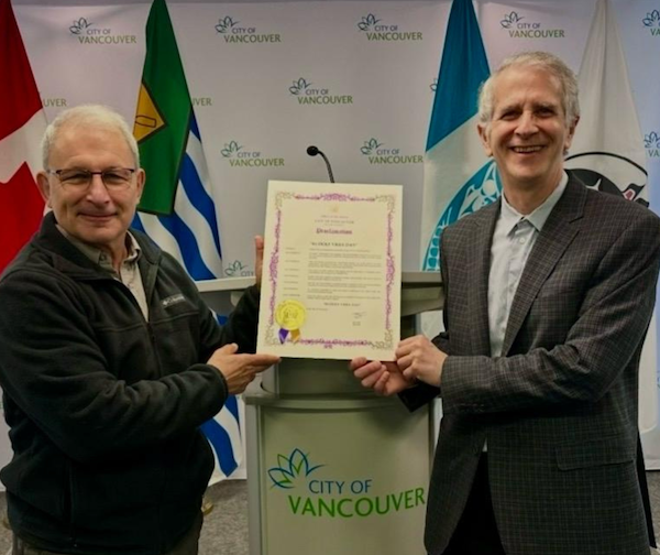 photo - Geoffrey Druker, left, and Glen Steinman hold the City of Vancouver proclamation of April 7, 2026, as Rudolf Vrba Day